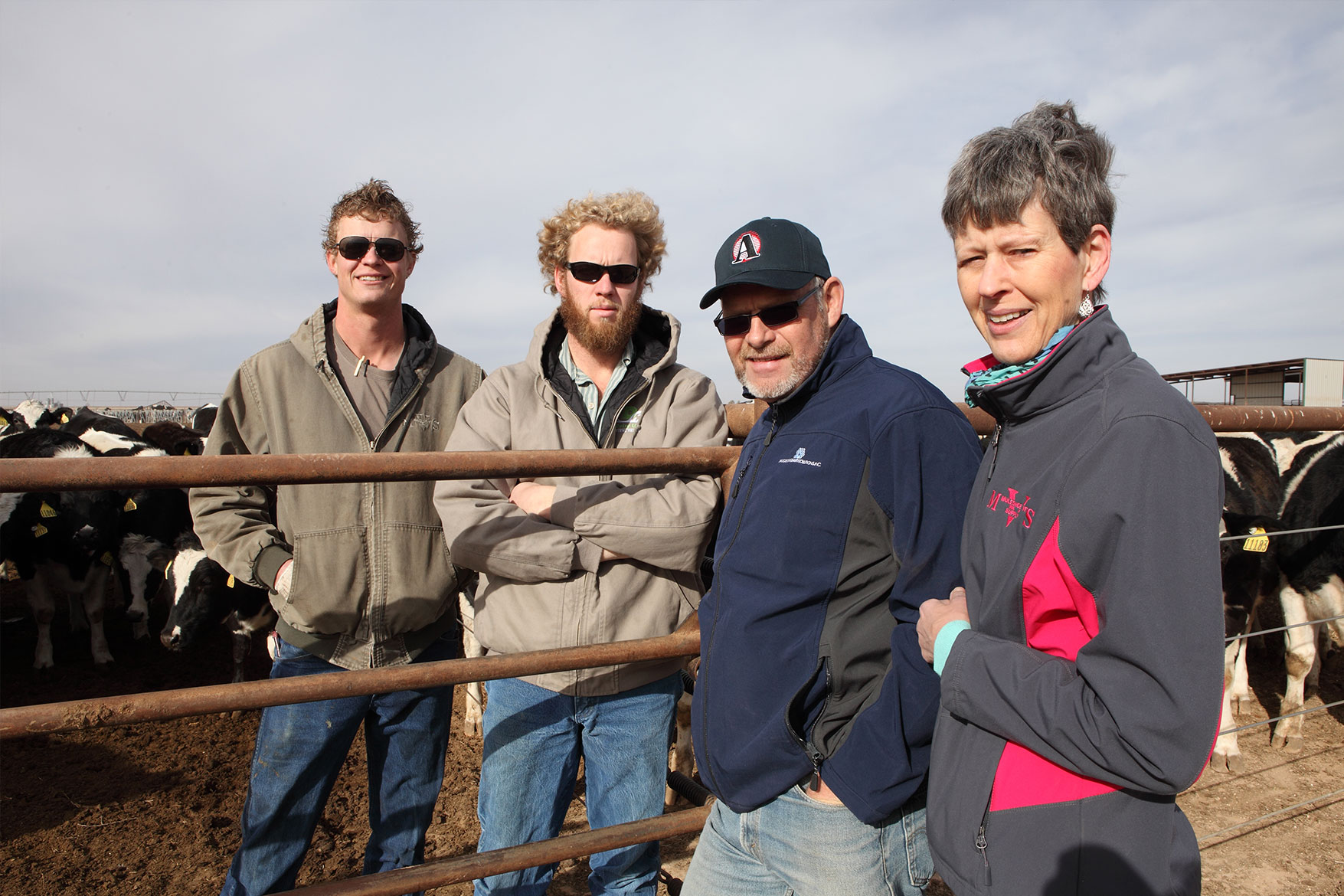 The DeVos family poses with curious Holsteins looking on.